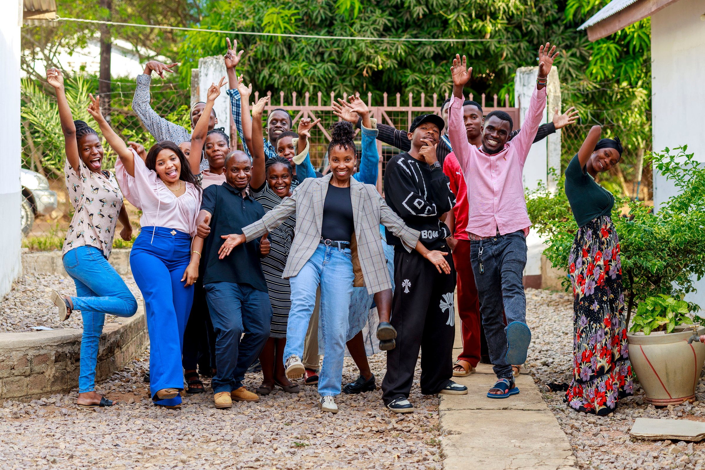 Young people and facilitators of the Safe Corner Project cheering together outdoors