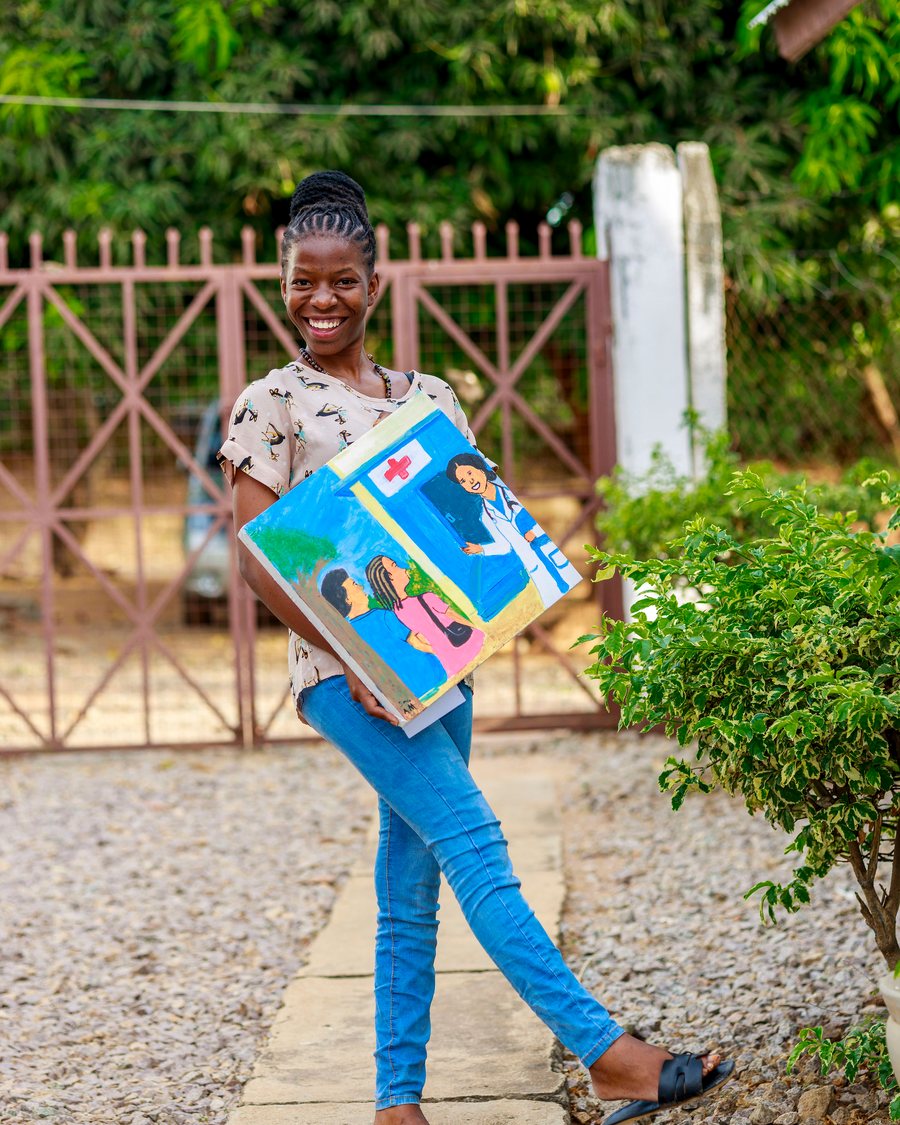A young woman holds up the health-rights painting she made